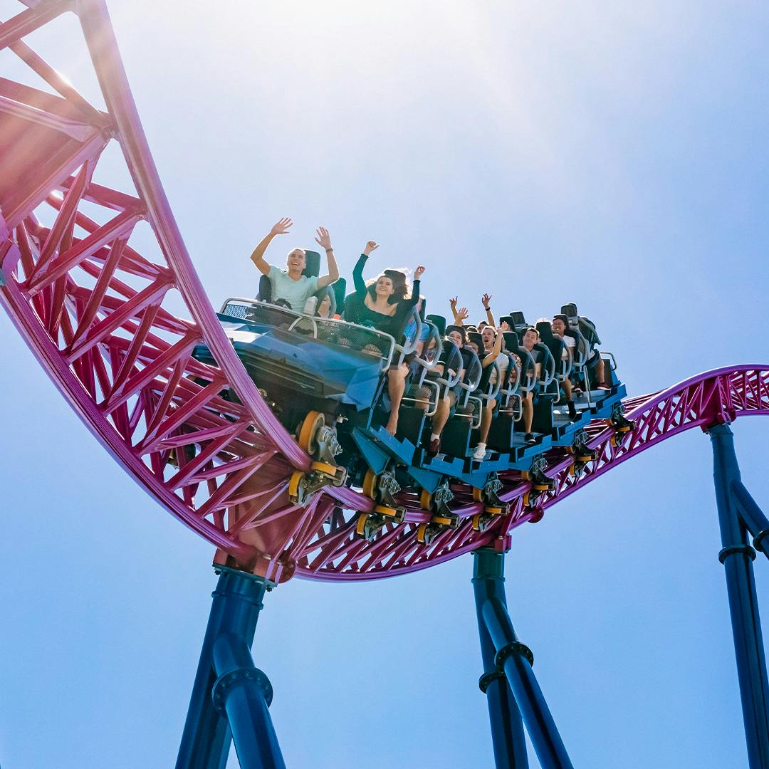 Excited riders with their hands up, enjoying the thrilling experience on the DC Rivals HyperCoaster at Warner Bros. Movie World, feeling the rush of high-speed twists and turns