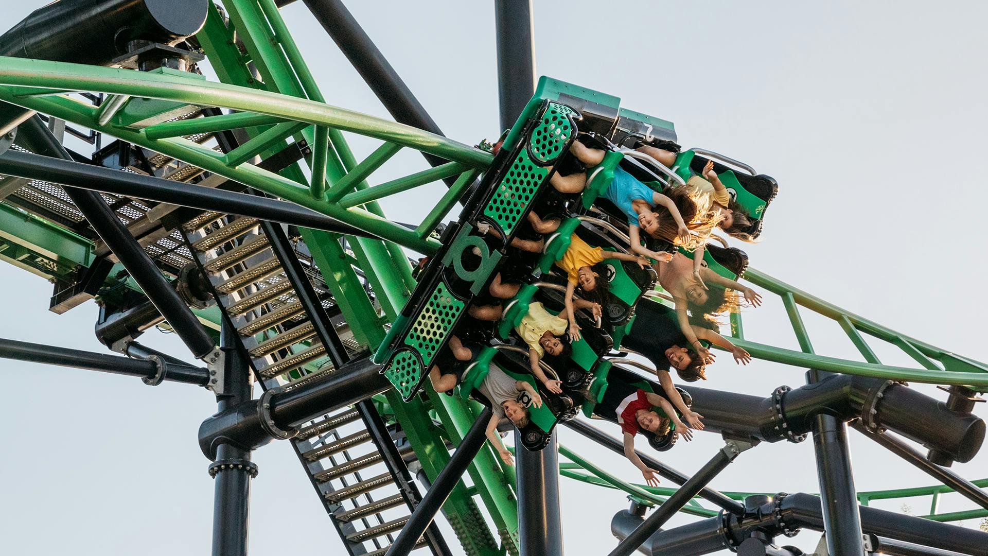 Thrilled riders upside down with their hands up, enjoying the exhilarating experience on the Green Lantern Coaster at Warner Bros. Movie World, feeling the rush of high-speed twists and turns